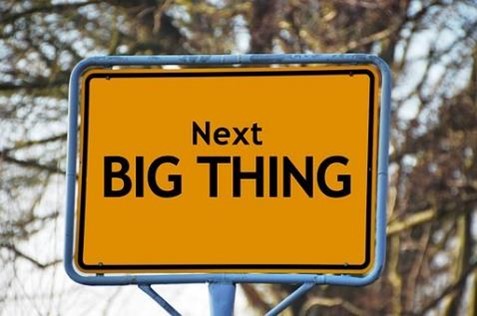 A yellow road sign that says, “Next big thing,” framed by a blue metal tube.