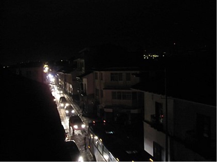 A line of vehicle headlights providing the only illumination during a blackout.