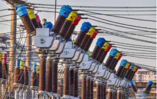 Colorful high voltage power transformers in two rows connected to wires.