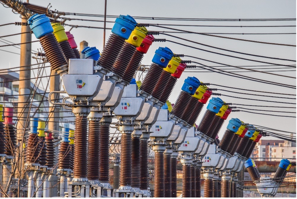 Colorful high voltage power transformers in two rows connected to wires.