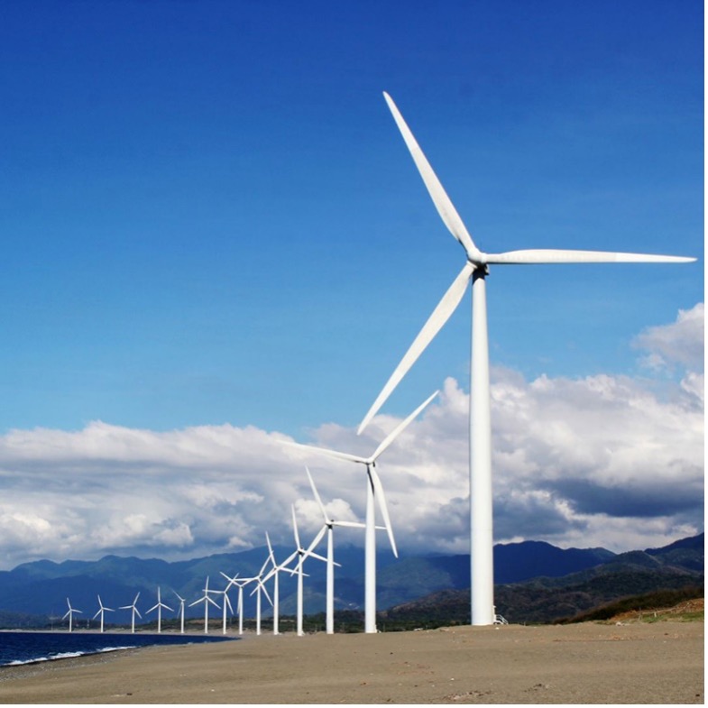 a long row of wind turbines with a background of a blue sky, clouds, and mountains.