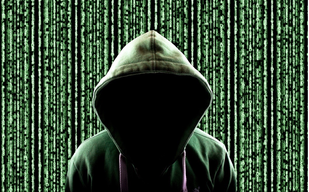 A hacker wearing a hoodie is at the middle and has data lined horizontally as the background, much like the poster from the movie, The Matrix.