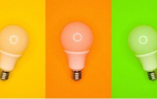 Three LED bulbs with yellow, orange, and light green as each of their backgrounds.