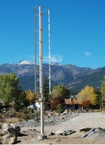 A Windspire vertical axis wind turbine installed and used as a power source close to a community in a mountainous area.